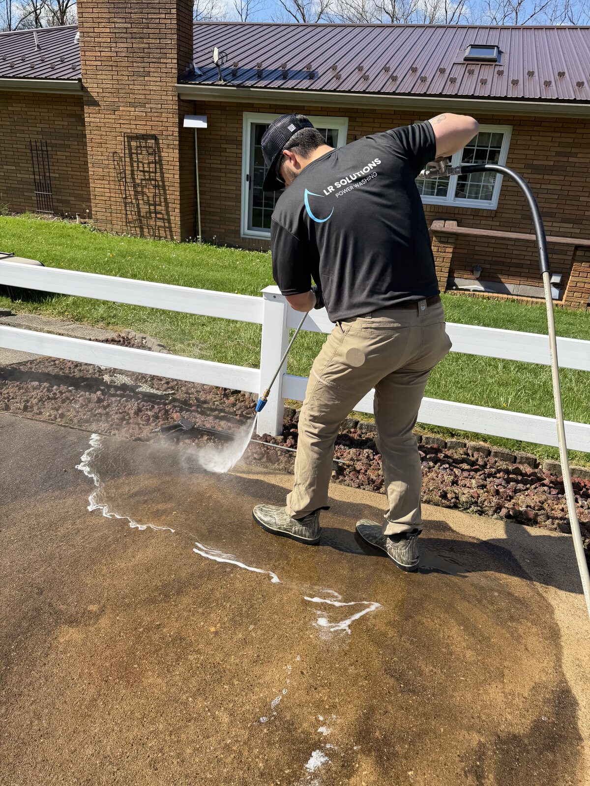 LR Solutions technician pressure washing a concrete walkway